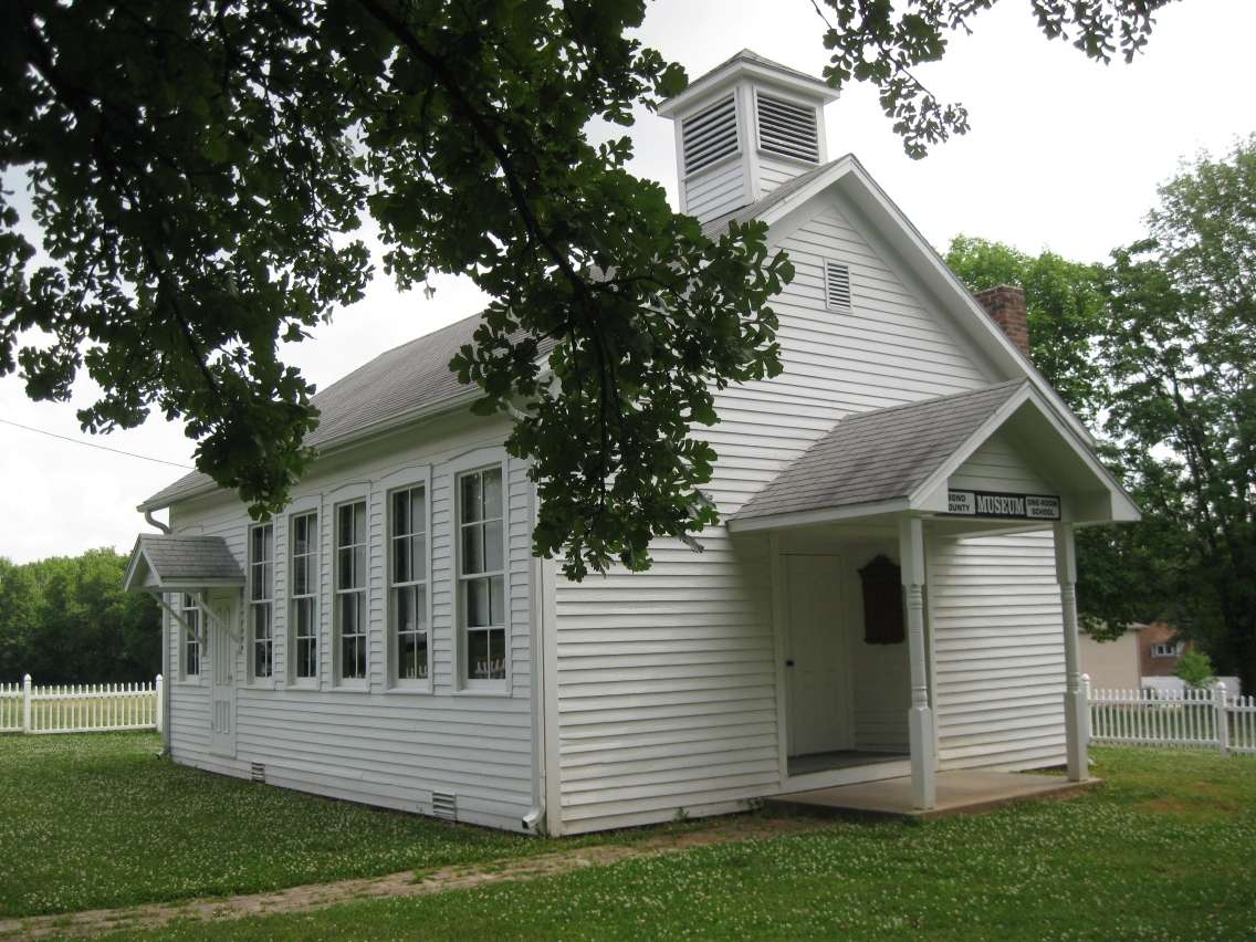 wood siding building painted white with tall narrow windows and two shingled awning entrances